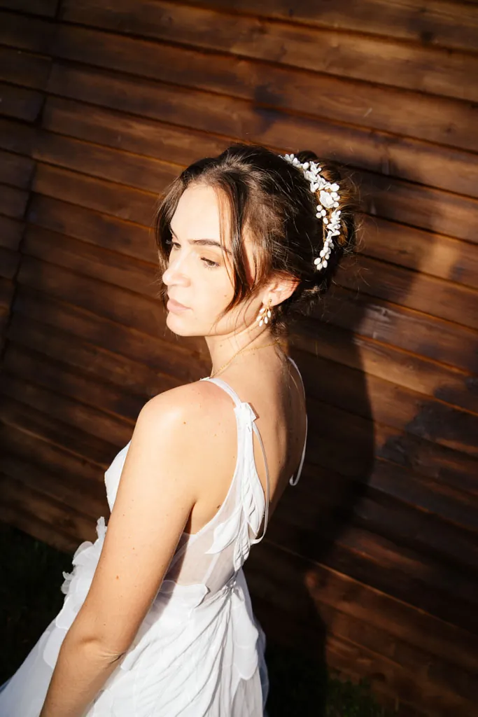 Portrait de la mariée et de sa couronne de fleurs devant un mur en bois