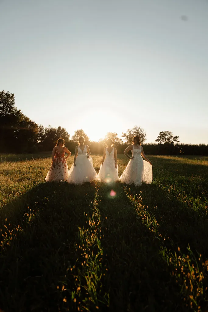 Les mariés et leur cortège dans un champ au coucher du soleil